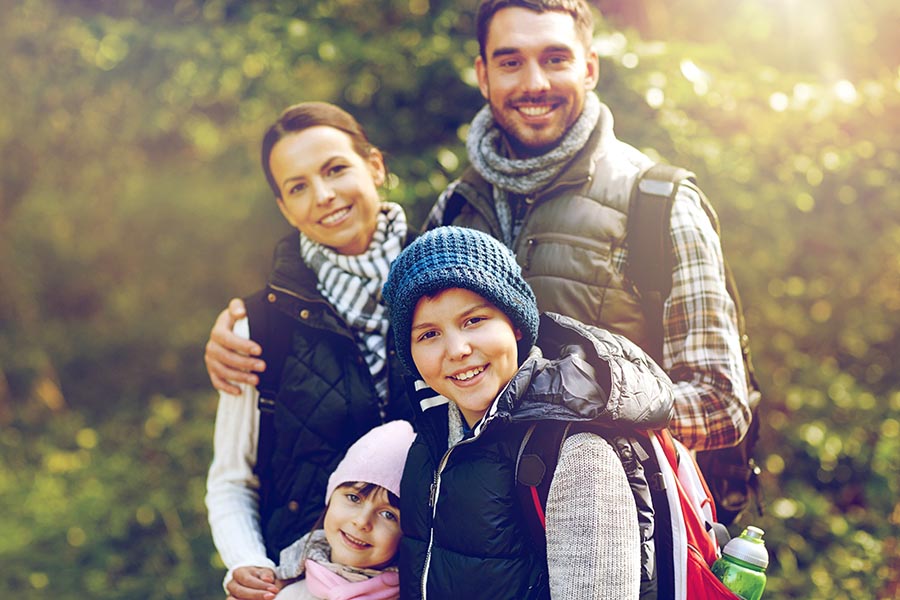 Personal Insurance - Mother, Father, Young Son and Daughter Bundled up for a Hike Outside With Trees